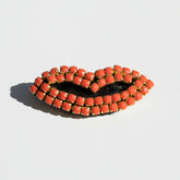 Bracelet with coral-colored beads on a light gray background