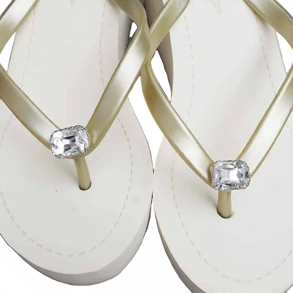 gold flip-flops with gold straps and clear gemstones on a white background